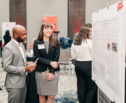 A man and woman standing next to a poster display.