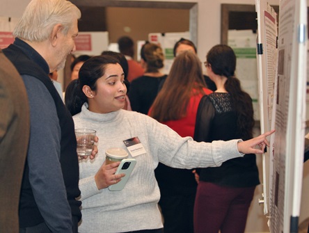 A man and woman standing next to a poster display.